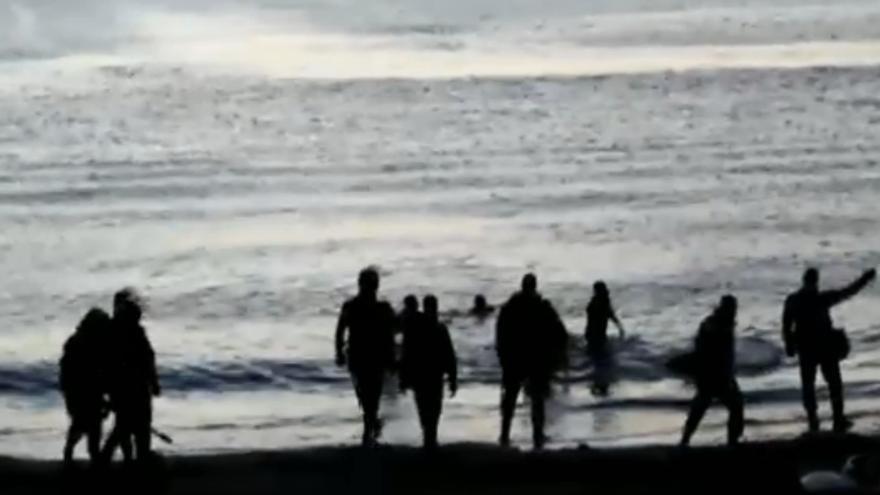 Imagen de la Guardia Civil con equipamiento antidisturbios recibiendo a los inmigrantes en la playa de Ceuta