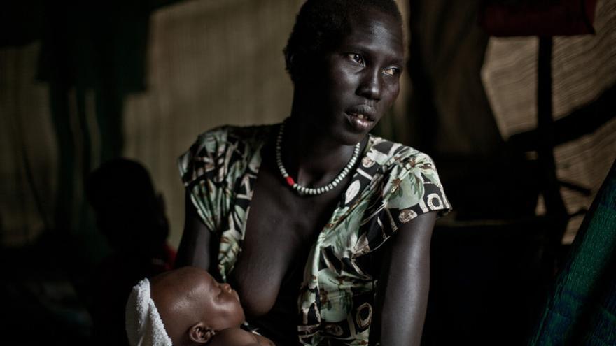 Mari Abrey dio a luz a un bebé en marzo de 2014 en Mingkaman. Cuenta las duras condiciones en las que tuvo el bebé dentro de la tienda y cómo llegó hasta allí. Tiene dos hijos más y alerta con su mirada la imposibilidad de alimentarlo  Ella es una de las casi 100.000 personas que viven en Mingkaman, el mayor campo de desplazados de Sudán del Sur. Aquí se instalan las personas que huyen de la violencia desde que empezó el conflicto en el país africano en diciembre de 2013. El campo de desplazados de Mingkaman, en Awerial, se ha convertido en refugio para casi 100.000 personas, principalmente de la etnia dinka, que huyeron de los enfrentamientos violentos en el estado de Jonglei, principalmente de la ciudad de Bor. Las personas que llegan necesitan agua, comida y un techo dónde refugiarse. Sudán del Sur afronta una grave crisis a causa de la violencia que se desató en diciembre de 2013 entre las fuerzas leales al presidente Salva Kiir, y los combatientes aliados al ex vicepresidente Riek Machar. Cerca de un millón de personas han tenido que abandonar sus hogares a causa de los enfrentamientos y se han quedado sin medios propios para alimentarse. Un tercio de la población sufre inseguridad alimentaria./Pablo Tosco/Oxfam Intermón