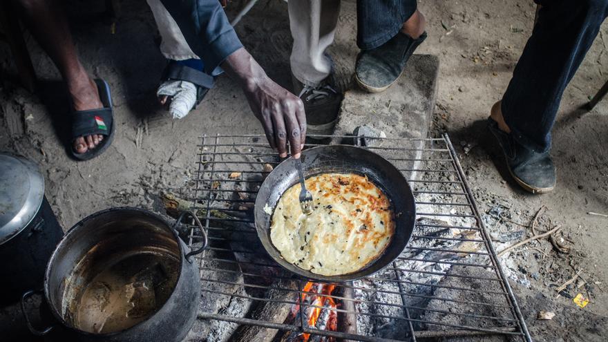 Refugiados sudaneses, algunos visiblemente heridos, cocinan al aire libre en el campamento de La Jungla, en Calais. / Foto: Thom Davies. 