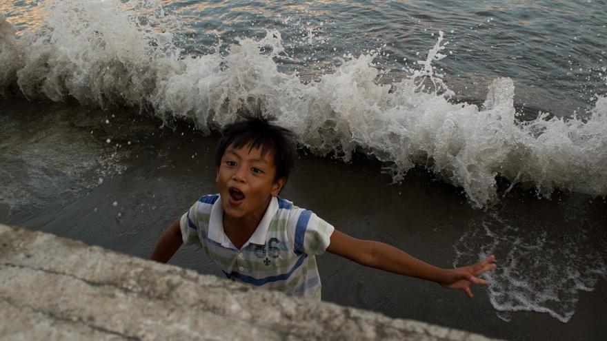 Un niño juega a refugiarse de las olas del mar en Tacloban (Filipinas). Foto: Carlos Sardiña Galache.