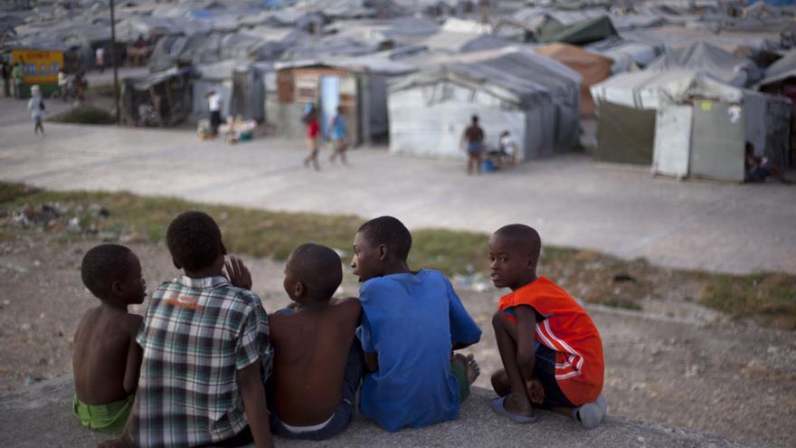 Un grupo de niños se sientane en la terraza de una casa dañada por el terremoto de 2010, frente al campamento de Jean Marie Vincent donde todavía residen, en Puerto Príncipe, Haití./ Fotografía: Nalio Chery (AP)