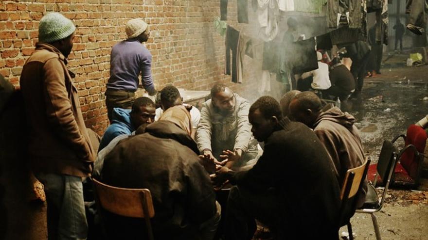 Un grupo de hombres se caliente en torno a un fuego en la Vandamme en Calais //FOTO: UNHCR /J. Pebrel