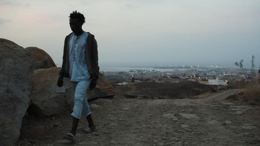 Adil Hamid, 25, de Camerún, camina por el monte Gurugú con Melilla a su espalda. /Fotografía: Ángel Navarrete. 