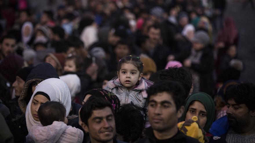 Una familia con su hija a hombros aguarda la llegada del ansiado ferry que los llevará a Atenas / Foto: Olmo Calvo 