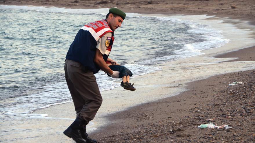 Un oficial de la policía paramilitar lleva el cuerpo sin vida de un niño refugiado después de que el barco en el que viajaba volcase junto a diezpersonas máscerca de la isla griega de Kos./ AP PhotoDHA