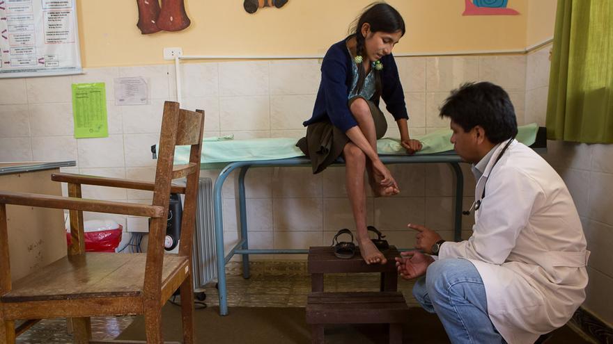 Nelida Llaveta tiene once años. En la foto, le explica al médico que desde hace unos días no puede caminar debido a un intenso dolor de rodillas. En Bolivia, la cobertura sanitaria es solo para menores de cinco años. El seguro de salud estudiantil garantiza la atención a todos los niños y niñas de 5 a 19 años de la comunidad de Sopachuy. (Salva Campillo/AEA).