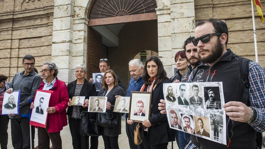 Familiares de fusilados por el franquismo sostienen los rostros de las víctimas frente a la Cárcel Modelo de Valencia