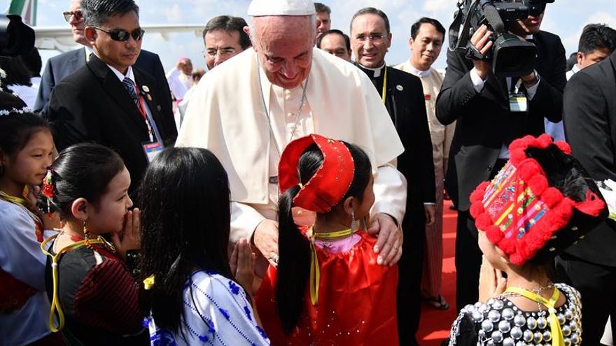 El papa Francisco saluda a un grupo de niños vestidos con trajes tradicionales a su llegada al aeropuerto internacional de Rangún (Birmania), este 27 de noviembre.