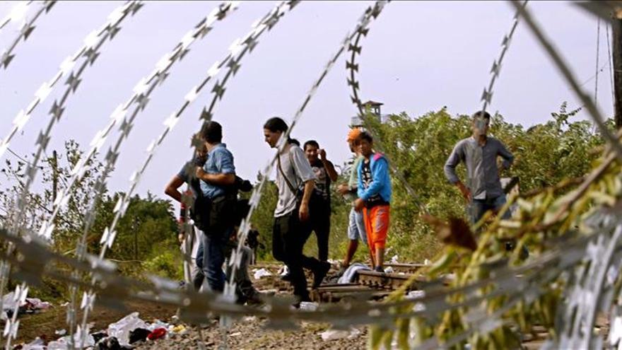 Migrantes son detenidos por una barricada en una vía férrea que conecta la frontera de Hungría con Serbia ayer, martes 15 de septiembre de 2015, en Röszke, Hungría./ EFE.