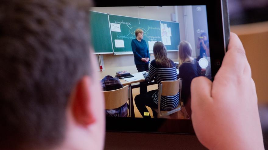 Un estudiante graba la imagen de la canciller Angela Merkel, de visita en una escuela de Berlín. 