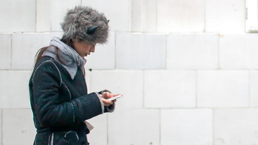 Una mujer anda por la calle mientras usa su teléfono móvil
