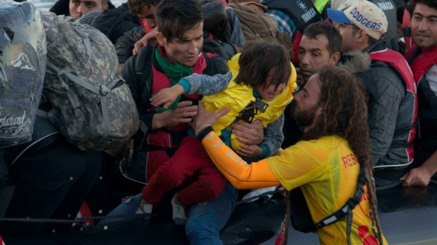 Un socorrista catalán de Proactiva toma en brazos a un niño refugiado a su llegada a Lesbos / Juan Carlos Mohr 