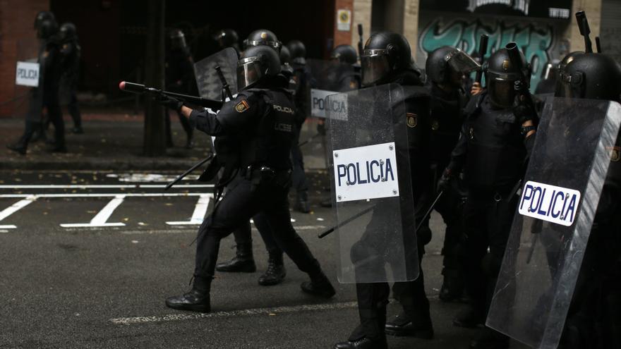 Descripción : A Spanish National Police officer aims ar rubber-bullet rifle at pro-referendum supporters in Barcelona Sunday, Oct. 1 2017. Catalonia's planned referendum on secession is due to be held Sunday by the pro-independence Catalan government but Spain's government calls the vote illegal, since it violates the constitution, and the country's Constitutional Court has ordered it suspended. 