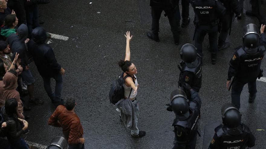 Descripción : A woman holds her hands up next Spanish National Police as they try to block voters from reaching a voting site at a school assigned to be a polling station by the Catalan government in Barcelona, Spain, Sunday, 1 Oct. 2017. Catalan pro-referendum supporters vowed Saturday to ignore a police ultimatum to leave the schools they are occupying to use in a vote seeking independence from Spain. 